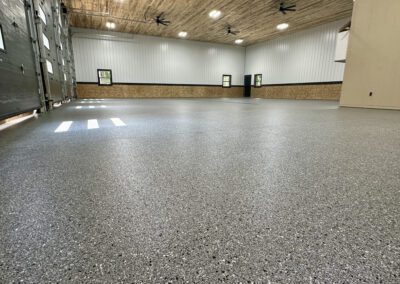 A spacious room featuring a large garage door and a ceiling fan, creating an open and airy atmosphere