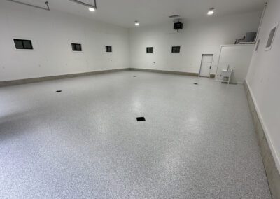 A spacious garage featuring a white floor and several windows, allowing natural light to illuminate the interior