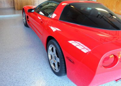 A red sports car parked inside a spacious garage, showcasing its sleek design and vibrant color