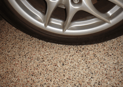 A close-up view of a tire resting on a garage floor, showcasing its texture and details against the concrete surface