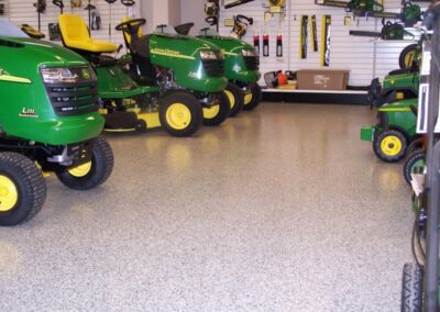 A spacious garage filled with multiple green lawn tractors, showcasing their vibrant color and sturdy design