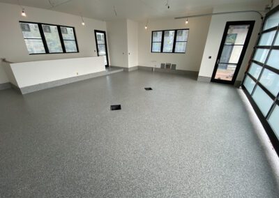 A spacious garage featuring a large door and a clean, concrete floor, ideal for vehicle storage and maintenance