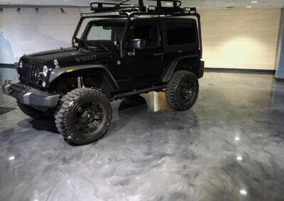 A black jeep parked inside a spacious garage, showcasing its sleek design and polished exterio