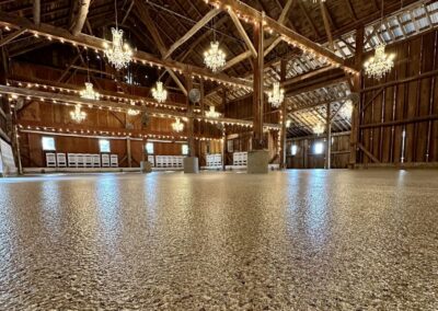 An expansive barn featuring beautiful chandeliers and arranged tables, creating a charming event space