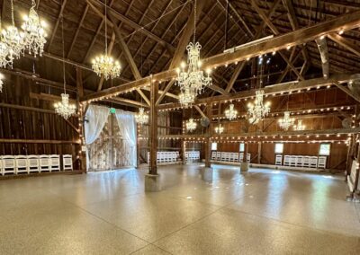 A spacious barn adorned with elegant chandeliers and set with tables for an event or gathering