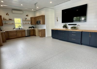 A stylish kitchen and living room combination showcasing a large flat-screen TV as the focal point of the space